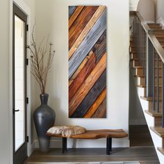 a painting on the wall next to a bench in a room with wooden floors and stairs