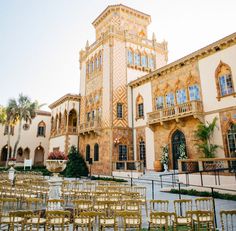 rows of gold chairs in front of a large building with windows and balconies