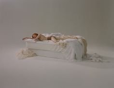 a naked woman laying on top of a white bed