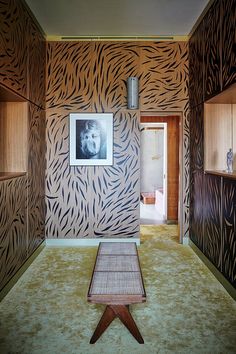 an animal print wallpapered room with a bench in the foreground and pictures on the walls