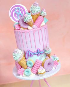 a pink and blue cake with ice cream, donuts, lollipops, marshmallows, pretzels and candy