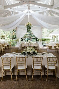 the tables are set up with white linens and gold chairs for an elegant reception