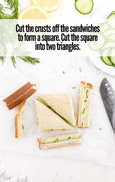 a sandwich cut in half with cucumbers on the side and sliced into two triangles