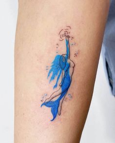 a woman's leg with a blue tattoo on it and an image of a mermaid