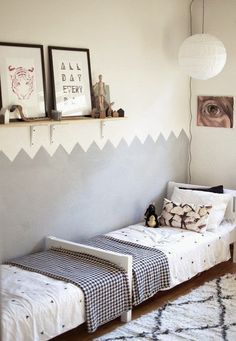 two twin beds in a bedroom with white walls and black and white decor on the wall