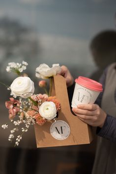 a person holding a coffee cup and some flowers