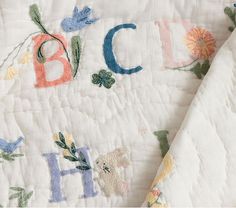 an embroidered quilt with the letters b, c, and h written in floral designs