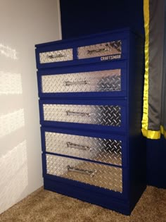 a blue metal drawer with yellow tape on the bottom and silver diamond plated drawers