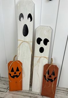 three halloween decorations made out of wood with faces and noses on them, tied to twine