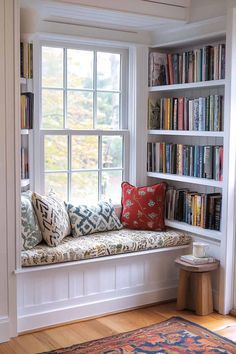 a window seat in front of a book shelf filled with books