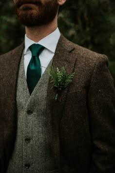 a man wearing a suit and tie with a green flower in his lapel pocket