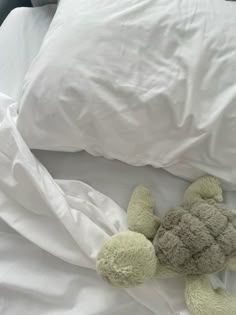 a stuffed animal laying on top of a bed next to white sheets and pillow covers