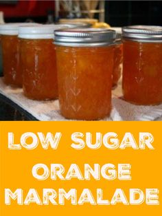 four jars of orange marmalade sitting on top of a counter with the words low sugar orange marmalade