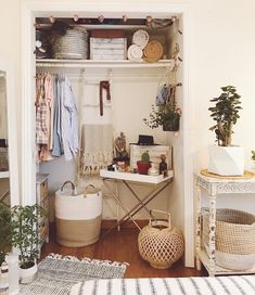 an open closet with clothes and baskets on the shelves, next to a bed in a bedroom