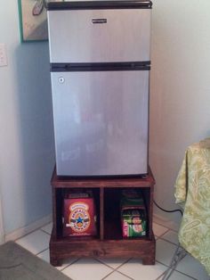 a silver refrigerator sitting on top of a wooden shelf