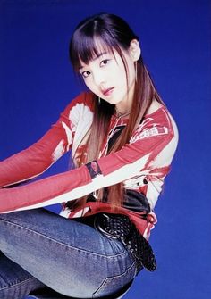 a young woman sitting on top of a chair wearing blue jeans and a red shirt