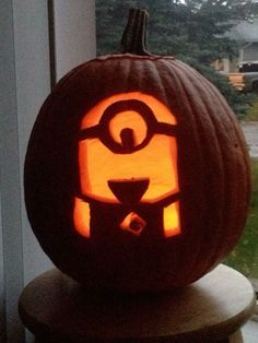 a carved pumpkin sitting on top of a wooden table in front of a window sill