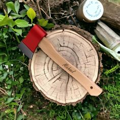 a red and black knife sitting on top of a tree stump next to other items