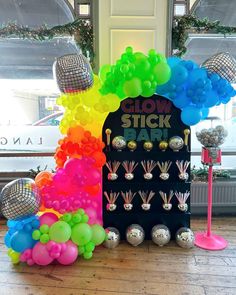 a display with balloons and disco balls in front of a sign that says glow stick bar