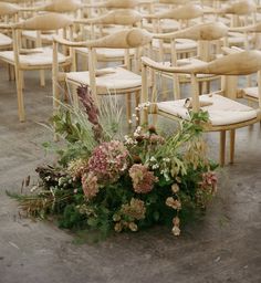 a bunch of chairs that are sitting in the ground with flowers on them and one chair is empty