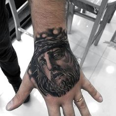 a man's hand with a tattoo on it and a jesus face in the middle