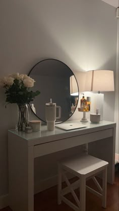 a white desk with a mirror, lamp and vase sitting on it's side