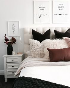 a white bed topped with lots of pillows next to a night stand and nightstands