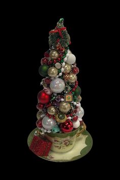 a small christmas tree with ornaments on it's top, sitting on a saucer