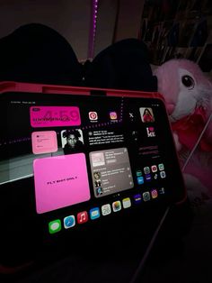 an ipad with pink stickers on it sitting next to a stuffed animal and other items