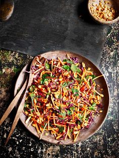 a salad with carrots, lettuce and other vegetables on a wooden plate