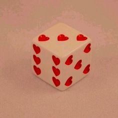 a white dice with red hearts on it