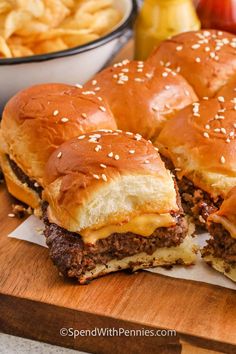 two cheeseburger sandwiches cut in half on a cutting board next to french fries