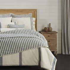 a bed with blue and white striped linens in a room next to a window