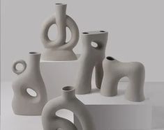 several white vases sitting on top of each other in different shapes and sizes,