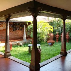 an outdoor area with potted plants and benches in the center, surrounded by greenery