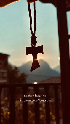 a bell hanging from the side of a wooden building with mountains in the back ground