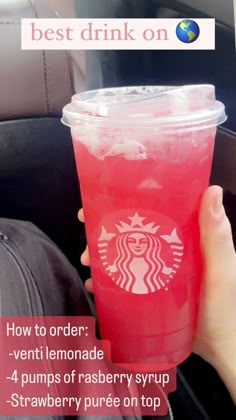 a person holding up a pink drink in their hand