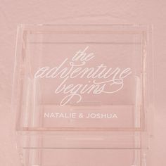 a clear acrylic sign with the words, the adventure begins and nathan & joshua