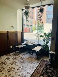 a room with two tables and a rug in front of a large window that looks out onto the street