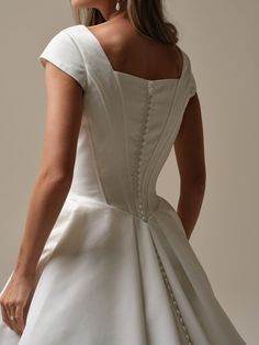 a woman in a white wedding dress with buttons on the back