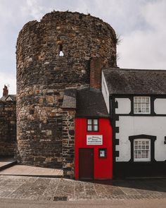 a small red and white building next to a tall brick tower with a sign on it