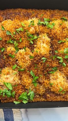 a casserole dish is topped with cheese and parsley on a marble countertop