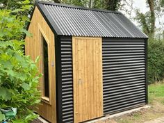 a small black shed with a wooden door