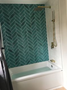 a bath tub sitting next to a shower in a bathroom with blue tiles on the wall