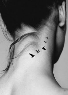 a woman's neck tattoo with birds flying in the sky on her left side