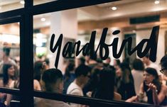 a group of people standing in front of a window with the word yardbird written on it