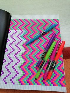 four pens are sitting on top of a colorful piece of paper that is lined up