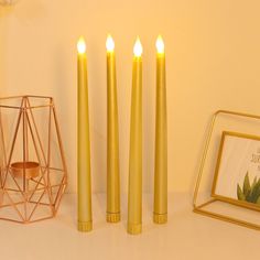 three candles sitting on top of a table next to a framed photograph and candle holder