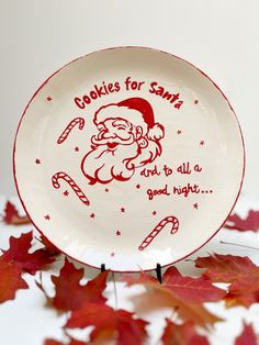 a plate with a santa clause on it sitting next to some leaves and candy canes