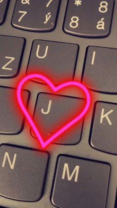 a red heart on top of a keyboard with the letters j and m underneath it